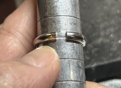 広げた状態の指輪を芯金に通して確認している写真