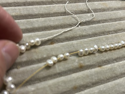 透明な石を新しいワイヤーに通す作業