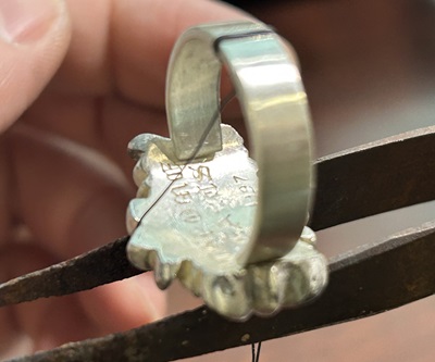 リングスタンドに固定してシャンクとコマパーツをロウ付け接合中の様子。裏面が見える。