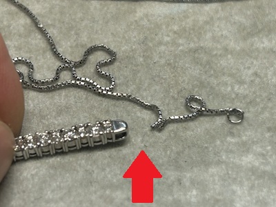 切れたチェーンとダイヤモンドバーペンダントが分離した状態、赤矢印がペンダントトップのバチカン（ジョー構造）を指示