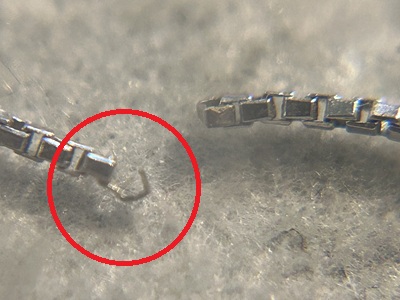 顕微鏡拡大写真、プラチナボックスチェーンの破断したリンク部分を赤丸で指示