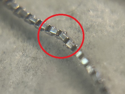 顕微鏡拡大写真、プラチナボックスチェーンの複数リンクが変形・傷んでいる箇所を赤丸で指示