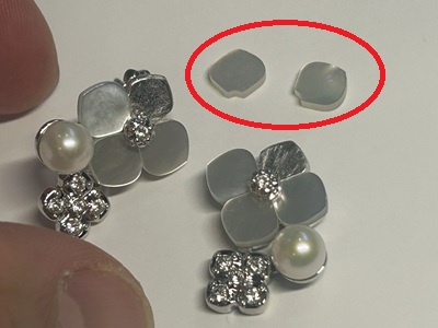 修理中のピアス本体2個と、交換用の半透明花弁パーツ2枚（赤丸で囲まれている）を並べた作業台の様子
