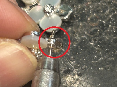 ピアスの新しいポスト（芯）をロウ付け・溶接で固定している作業、赤丸で接合部を指示