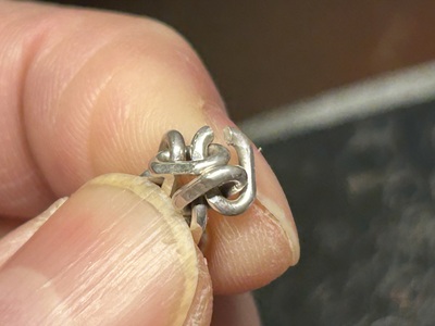 シルバーネックレスの切れたパーツを手元で確認している様子