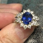 修理が完了し、すべてのダイヤモンドが美しく輝くサファイア指輪を指に着けた様子