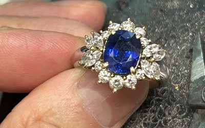 修理が完了し、すべてのダイヤモンドが美しく輝くサファイア指輪を指に着けた様子