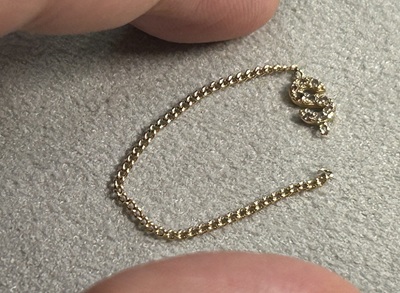 センターにダイヤモンドの「S」がついた、切れてしまったゴールドのチェーンリング