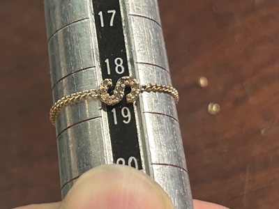 完成したリングをサイズ棒に乗せ、報告用の写真を撮影している様子