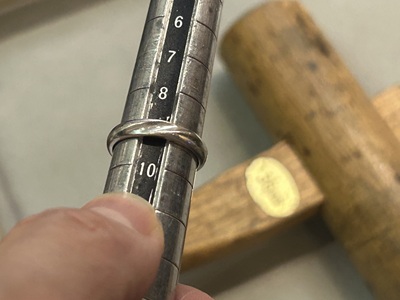 サイズ棒と木槌を使い、指輪の形を整える職人の手元