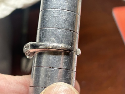 職人がサイズ棒と木槌を使ってプラチナリングを17号へ広げる作業