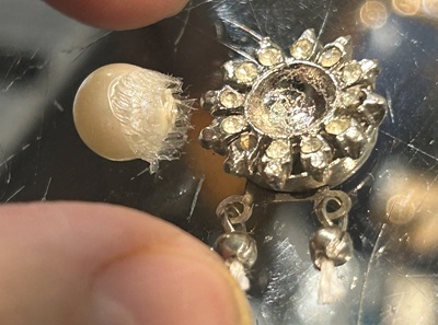 古い金具から大量の古い接着剤をこそぎ落として取り外された一粒の真珠
