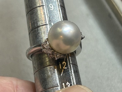 サイズ棒に通して真珠の指輪の現在のサイズが11号であることを計測している様子