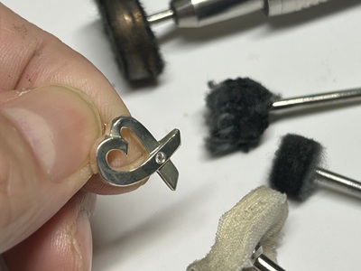 職人が手にする磨き加工前の黒ずんだシルバーハートペンダントトップ