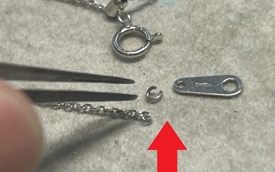ピンセットで示された外れた小さなマルカンとネックレスのプレートパーツ