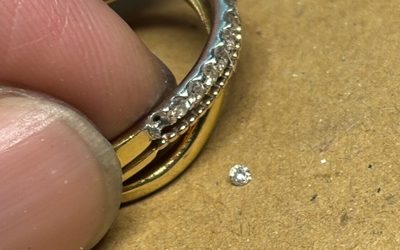 石が外れたリングの横に選定された小さなメレダイヤモンドが置かれている画像
