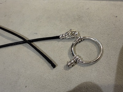 金具から黒い革ひもが完全に抜けて分離してしまっているシルバーのグラスホルダー