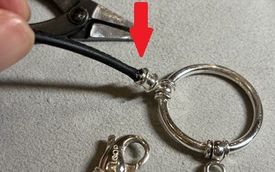 赤い矢印が示された、革ひもが金具へしっかりと再固定された完成状態