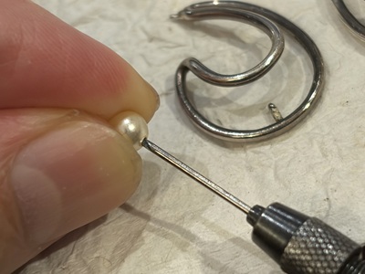 真珠の穴に残った接着剤をドリル針でお手入れしている様子