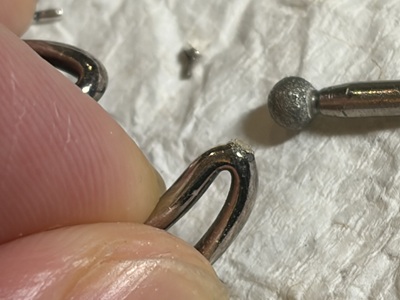 ピアス本体の接合部を平らに削り、小さな穴を開けている手元
