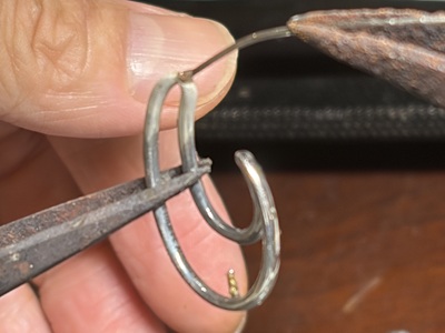 ピンセットで0.85mmの丸線を本体の穴に差し込み保持している様子